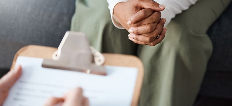 Healthcare working asking a client questions and using a clipboard.