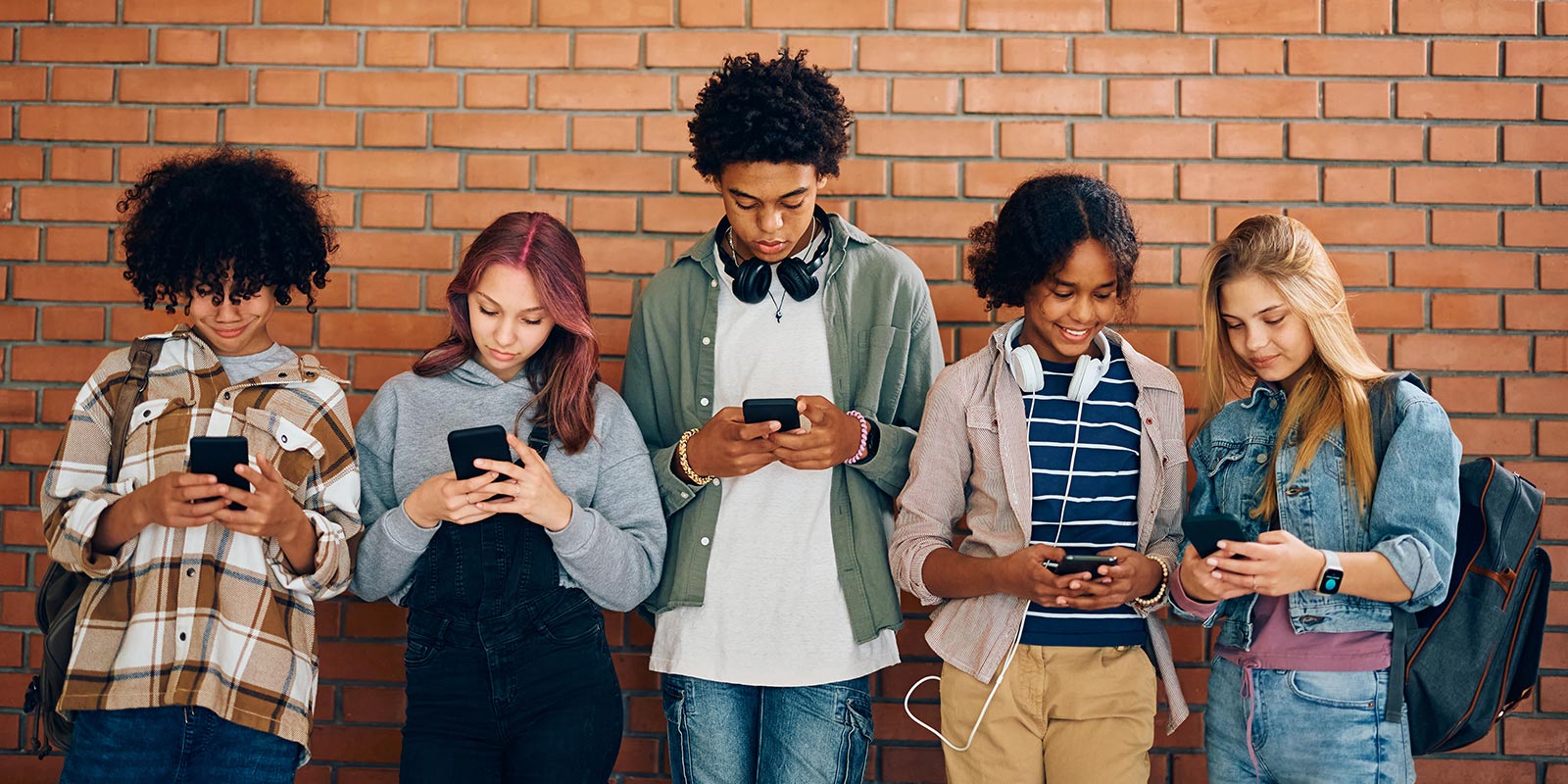 Group of diverse high school student's looking at their phones.